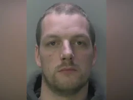 Mugshot of a man with short hair and stubble, looking straight ahead.