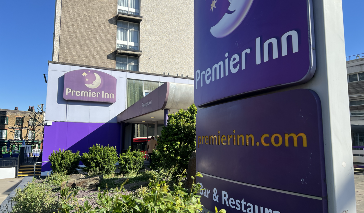 Exterior of Premier Inn hotel with a large purple sign and blue sky above.