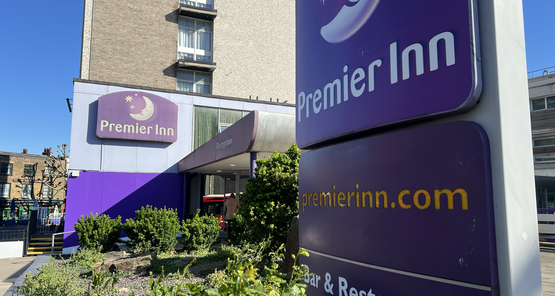 Exterior of Premier Inn hotel with a large purple sign and blue sky above.