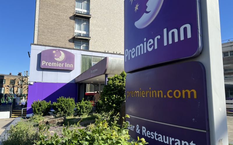 Exterior of Premier Inn hotel with a large purple sign and blue sky above.