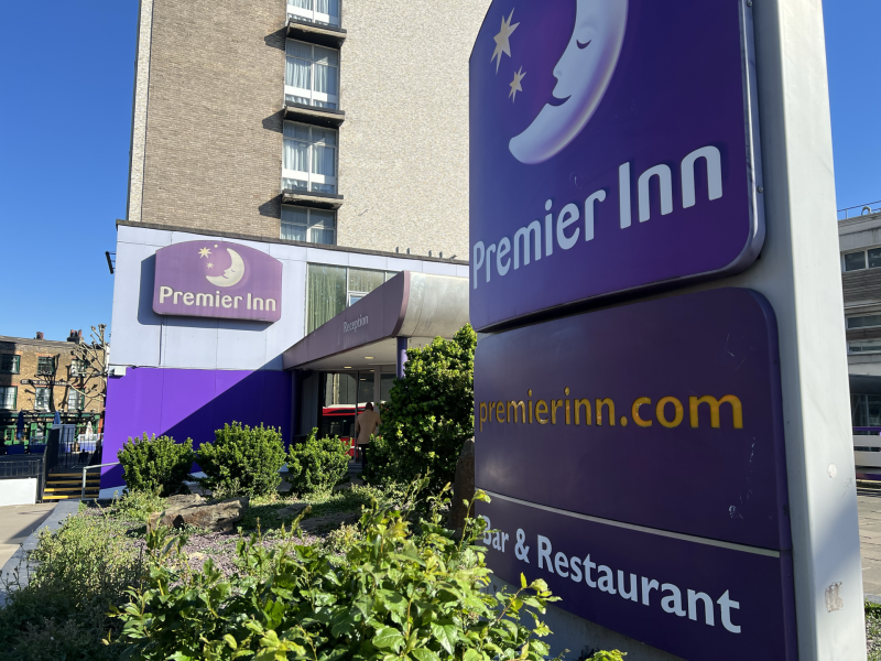 Exterior of Premier Inn hotel with a large purple sign and blue sky above.