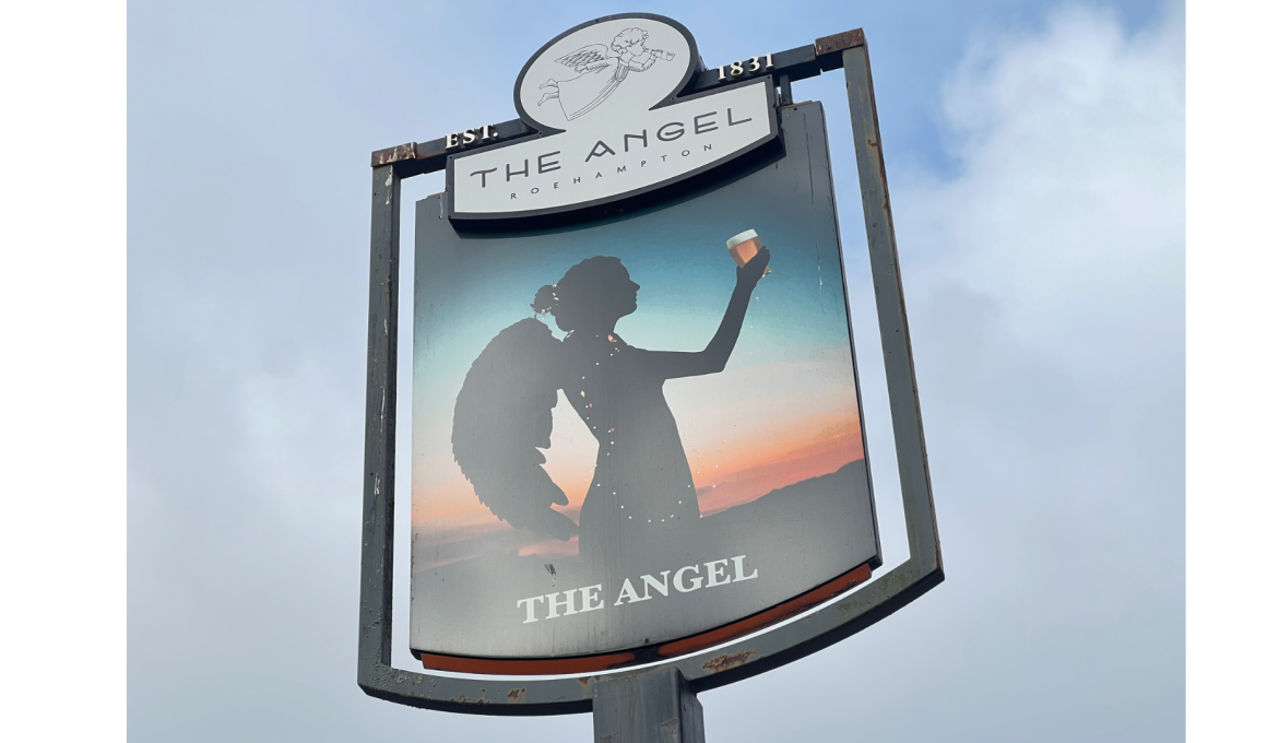Signboard for The Angel pub showing a silhouette of a woman raising a glass against a sunset, with EST. 1831 at the top