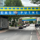 Colorful blue and yellow overhead bridge reading 'EAST PUTNEY' over a busy street with pedestrians and cars underneath.