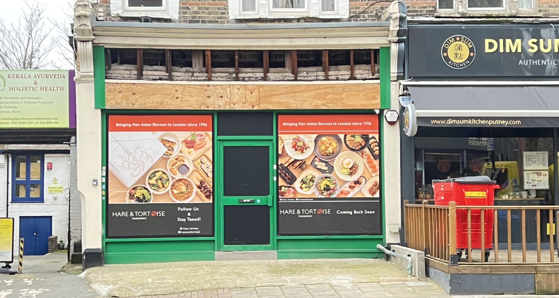 Row of shopfronts on a street: left Kerala Ayurveda sign, middle green-framed storefront with large food posters, right Dim Sum Kitchen signage.
