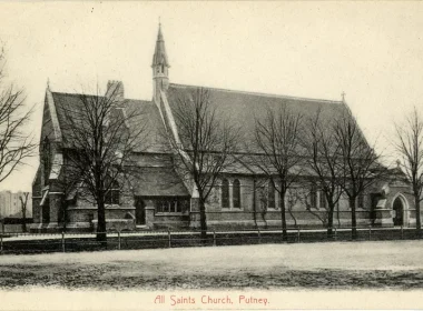 Vintage photograph postcard of All Saints Church, Putney: a long Gothic-style church with a tall spire, arched windows, bare trees lining the front yard, and a low fence along the street.