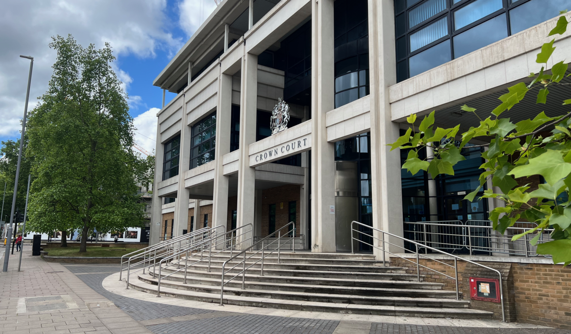 Front of Crown Court building with tall concrete columns, steps, and crest above the entrance.