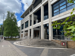 Front of Crown Court building with tall concrete columns, steps, and crest above the entrance.