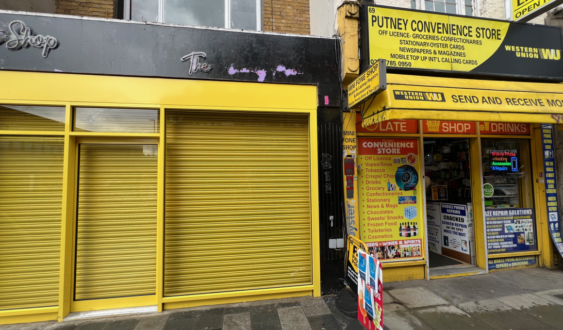 Bright yellow storefronts with closed shutters; 'Putney Convenience Store' sign and advertising boards on the right.