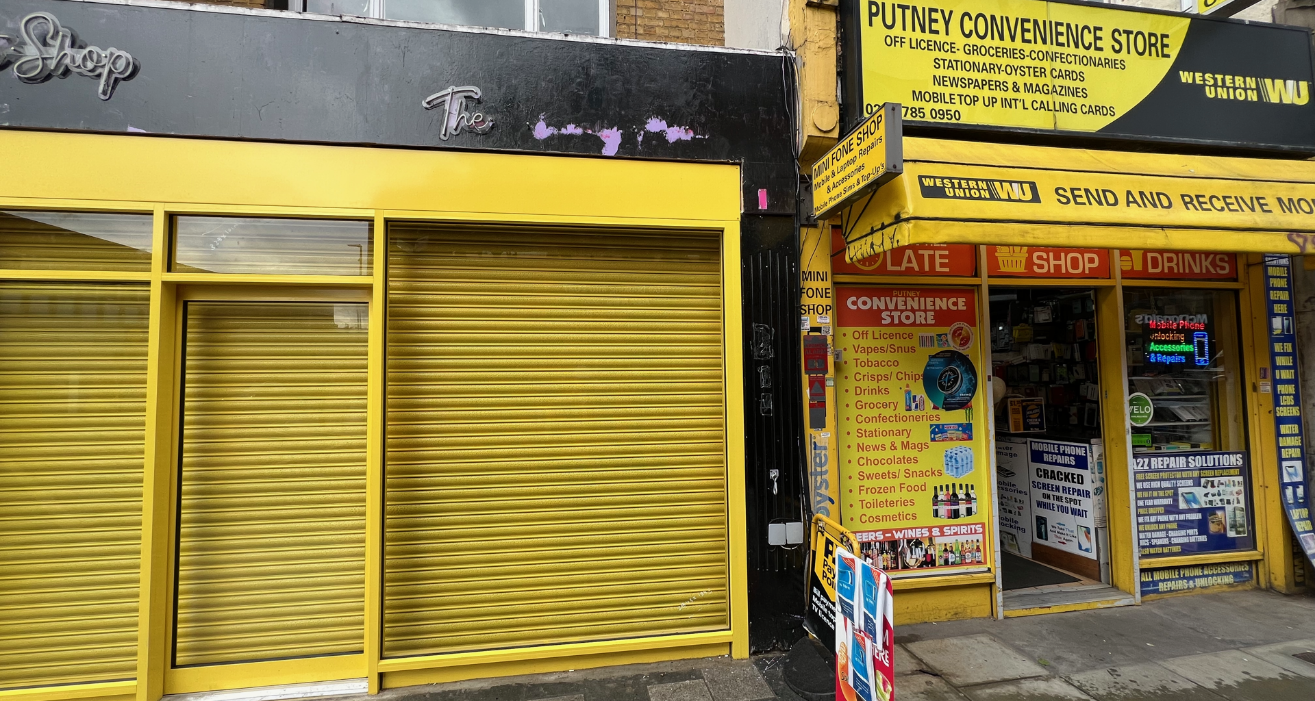 Bright yellow storefronts with closed shutters; 'Putney Convenience Store' sign and advertising boards on the right.