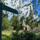 Green signpost pointing to St Margaret's, Putney, mounted on a teal metal pole with leafy background.