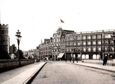 Historic street on a bridge with ornate lampposts and brick buildings along the riverfront (black-and-white).