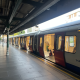 London Underground train at a platform with doors open and passengers inside, station signs visible.