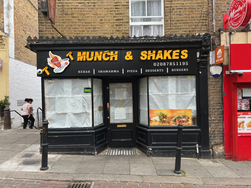 Front of a kebab shop with a black facade and large yellow sign: 'MUNCH & SHAKES' above the windows.