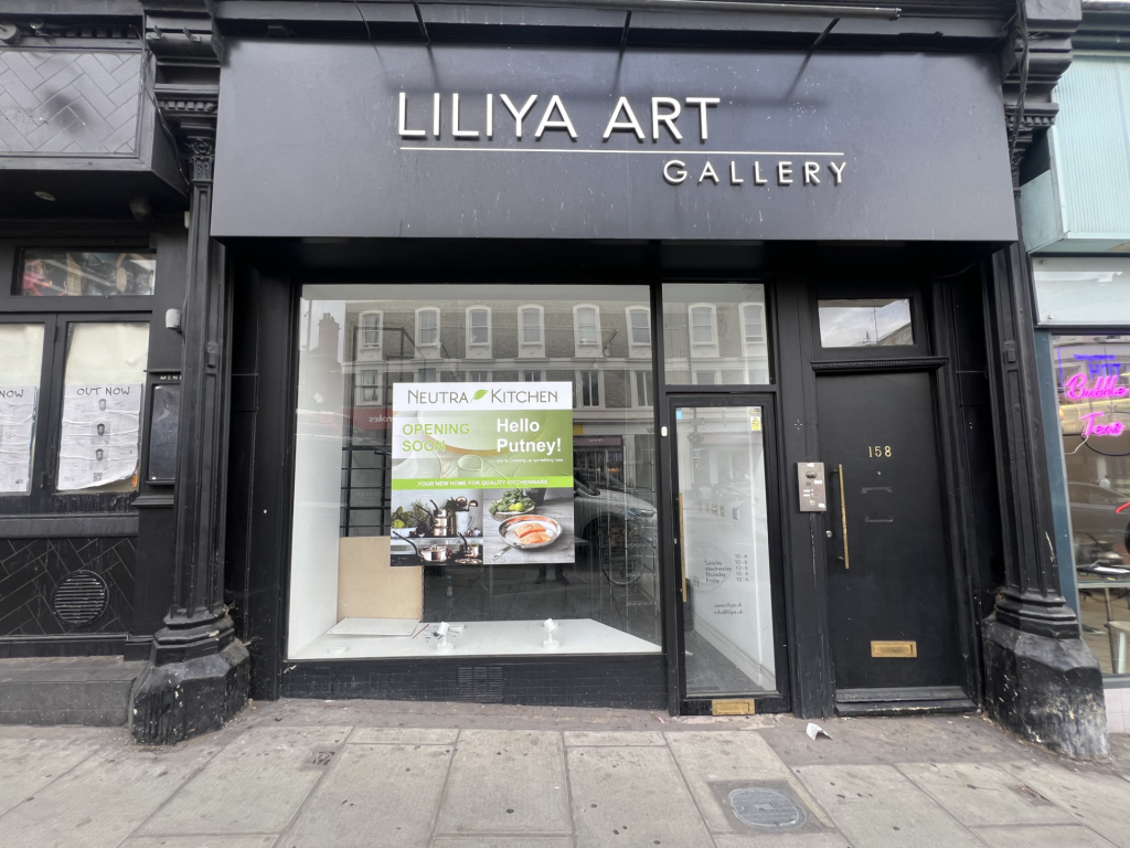 Front of Liliya Art Gallery: black storefront with a large window display and promotional posters in the glass pane.