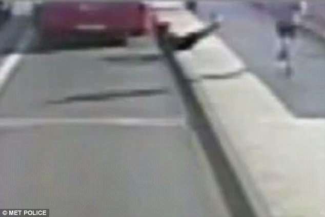 Blurred surveillance image of a person near a curb beside a parked vehicle on a city street (MET Police watermark).