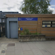 Exterior view of a Metropolitan Police outpost with a blue sign, wooden panel facade, and bulletin board windows on a city street.