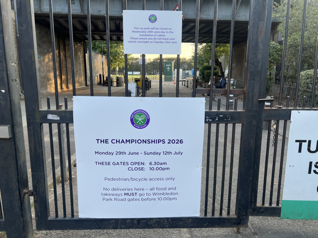 Wrought-iron gate with a large white poster announcing The Championships 2026 dates and entry rules.