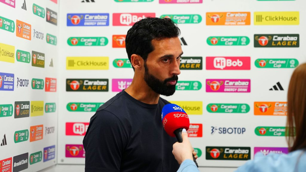 Álvaro Arbeloa in a dark Fulham training top, speaking into a Sky Sports microphone held by an interviewer, in front of a backdrop of Carabao Cup and sponsor logos.