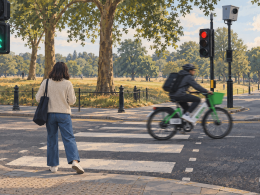 Pedestrian steps back as an electric hire bike rides through a red light across a London pedestrian crossing