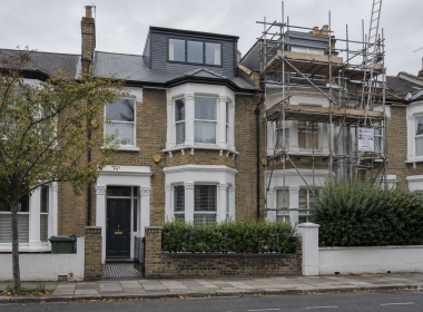 Victorian terraced houses on a quiet southwest London street, with a loft dormer extension and scaffolding covering one property beneath an overcast sky.