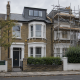 Victorian terraced houses on a quiet southwest London street, with a loft dormer extension and scaffolding covering one property beneath an overcast sky.