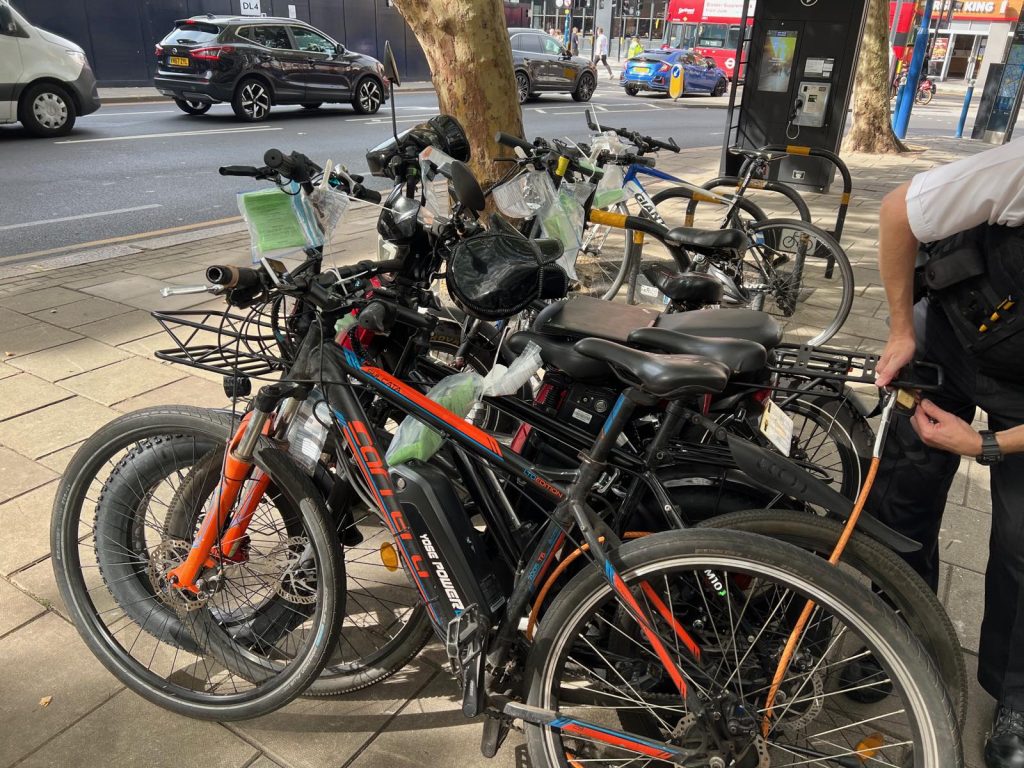 Seized bikes lined up by the kerb, each tagged with an evidence bag. Pic: Putney.news
