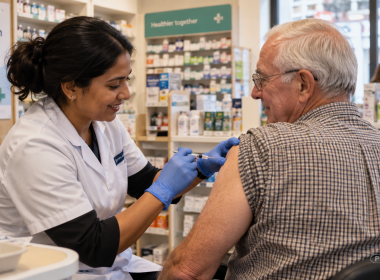 Pharmacist administering a vaccination to an older man in a neighbourhood pharmacy