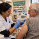 Pharmacist administering a vaccination to an older man in a neighbourhood pharmacy