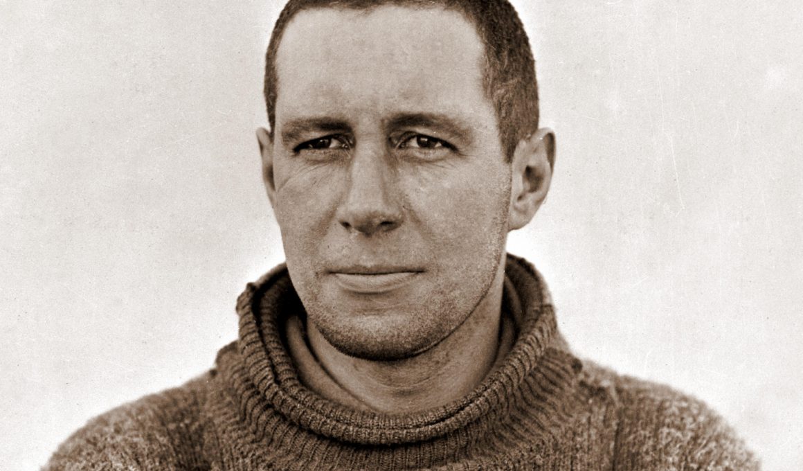 Black and white portrait of Lawrence Oates, head and shoulders, in a thick roll-neck jumper, looking straight at the camera.