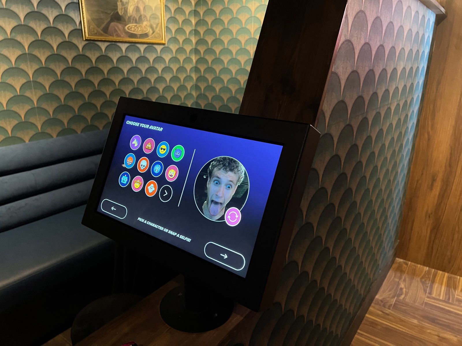 A lane touchscreen inviting players to choose an avatar or take a selfie