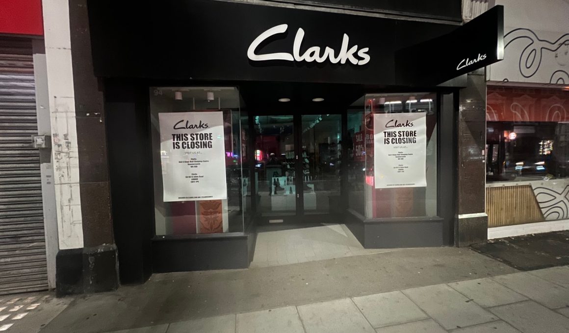 Clarks shopfront at 94 Putney High Street at night, with a "This store is closing" poster in each window