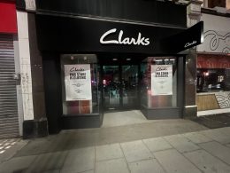 Clarks shopfront at 94 Putney High Street at night, with a "This store is closing" poster in each window