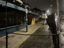 The closed Dynamo on Putney Bridge Road at night, its wooden terrace running along the kerb in front of it, with cycle stands on the decking and a new timber hoarding over the unit next door