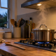 Stainless steel saucepan simmering over a blue gas flame on a kitchen hob, with steam rising beneath an extractor hood.