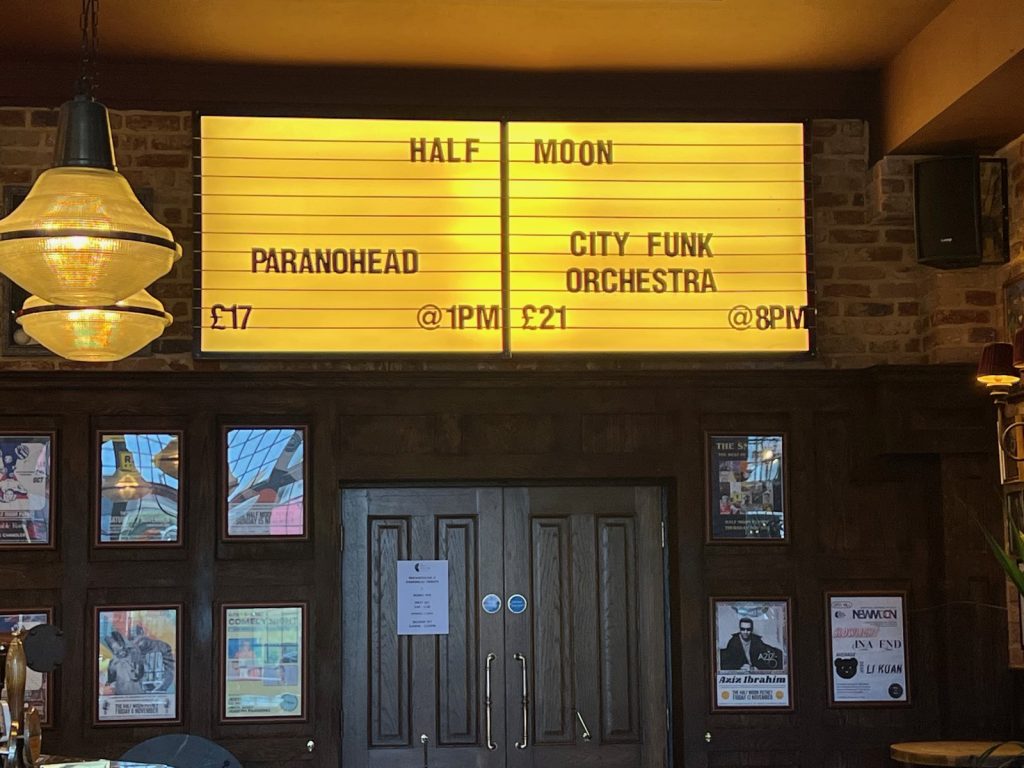 The Half Moon’s illuminated listings board showing Paranohead at 1pm for £17, beside City Funk Orchestra at 8pm.