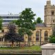 St Mary’s Church in Putney seen from Putney Bridge, with its stone tower, tall windows and trees beside the river