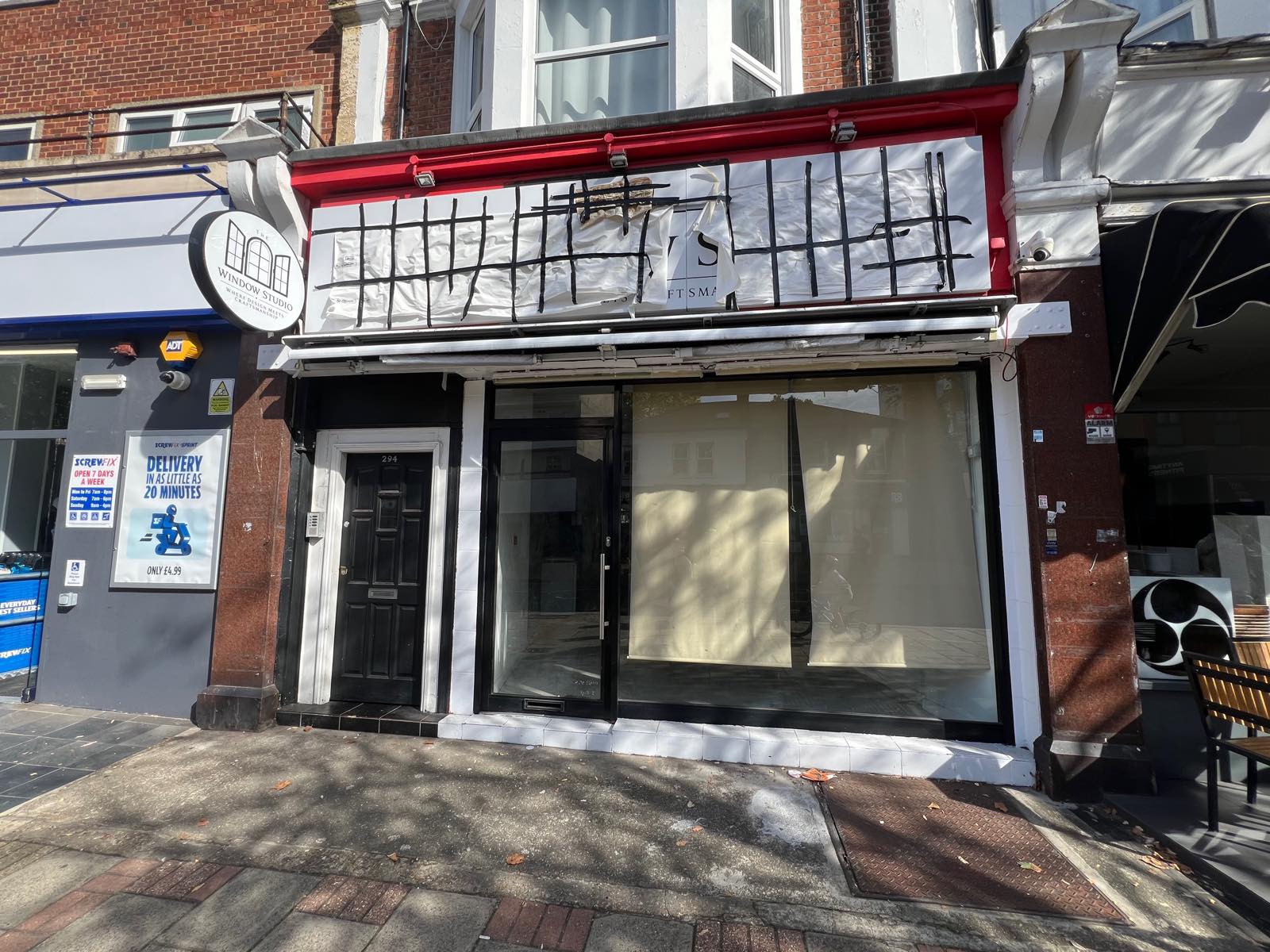 Shopfront at 294 Upper Richmond Road with a round Window Studio sign and the fascia covered in taped paper
